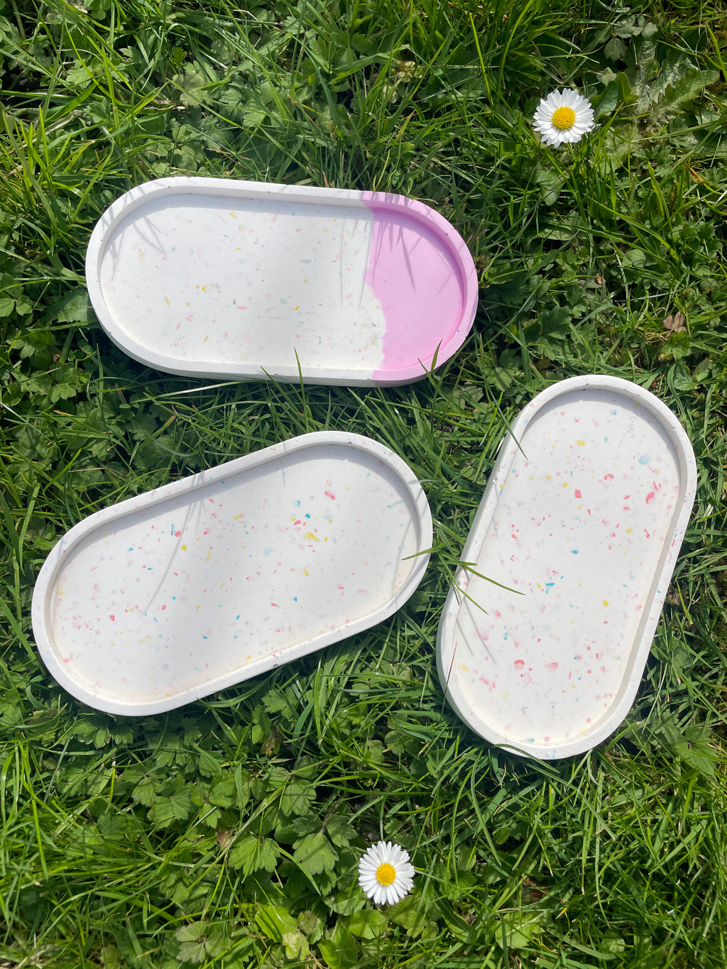 Collection of oval trays on grass in sun.