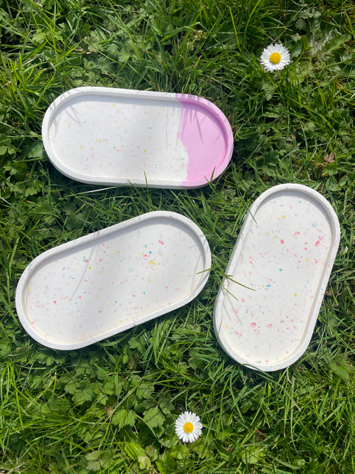 Collection of oval trays on grass in sun.